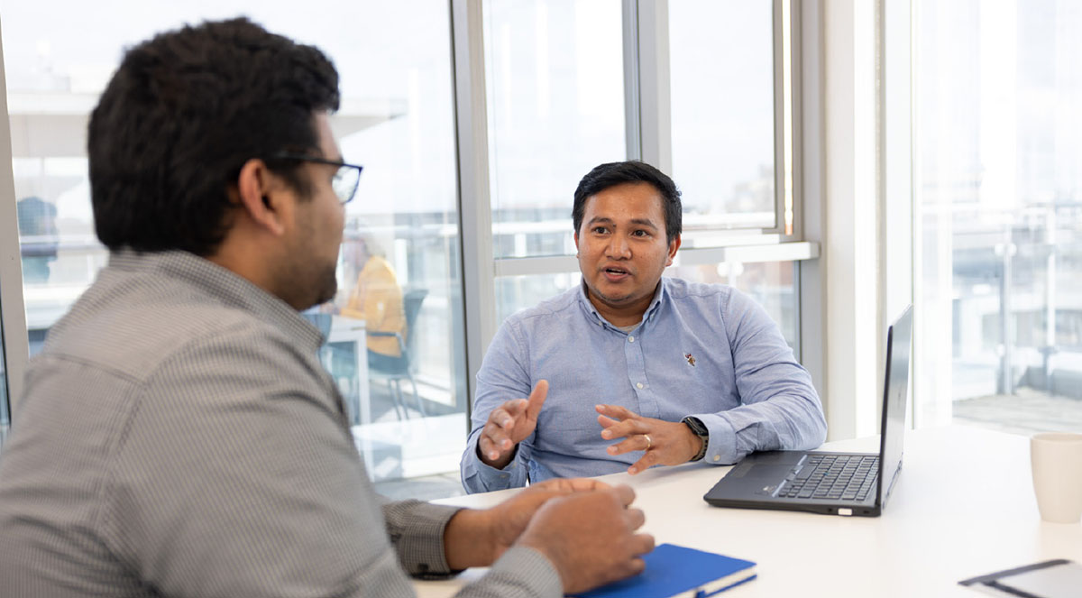 2 male admin staff in a meeting room with laptop