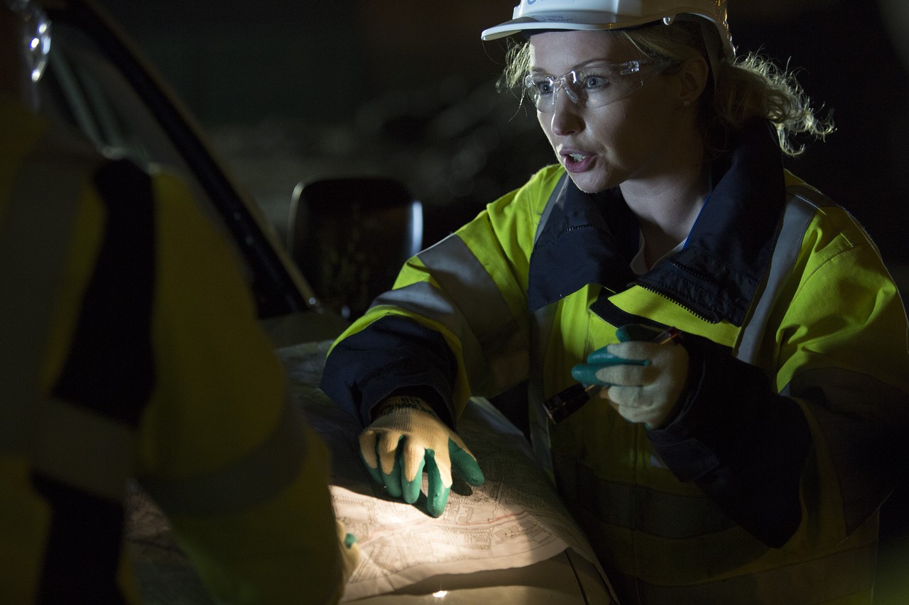 A person using a torch to see plans during night time