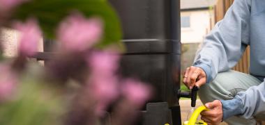 A person filling a watering can in a garden