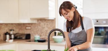 A woman washing lettuce in the kitchen sink