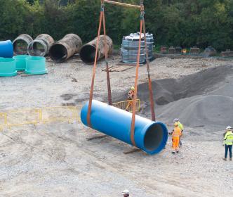 Construction site pipes being lifted by crane