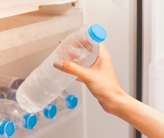 A person taking a cold water bottle from the fridge