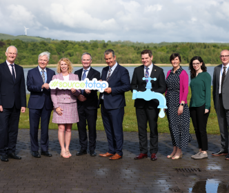 A group of people holding a sign with "#sourcetotap"