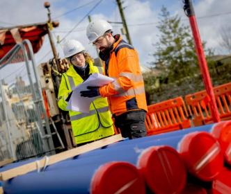 An Uisce Éireann engineer in front of a digger during road works